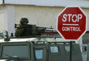 An armed man, believed to be Russian serviceman, stands guard outside an Ukrainian military base in Perevalnoye